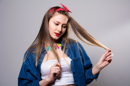 Portrait of a young woman in a jeans jacket on a gray background. Fashion Girlの写真素材