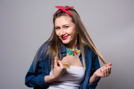 Smiling young woman in jeans jacket on a gray background. Fashion Girlの写真素材