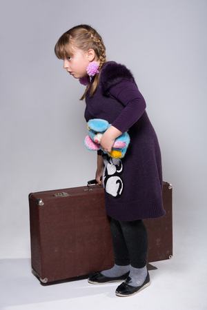 Teenage girl with a large old suitcase and a plush toy in her handの写真素材