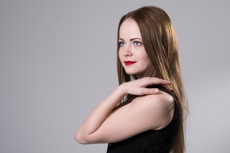 Close-up portrait of a beautiful woman with hand on shoulder. Beautiful girl in a black dress...