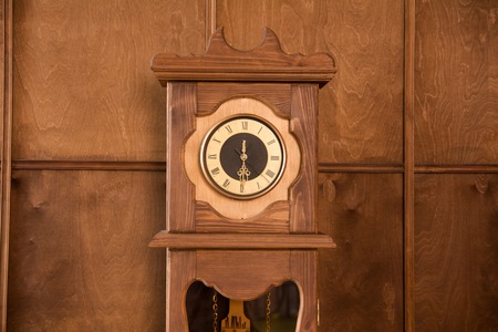 Close-up of a vintage outdoor clock on a wooden wall backgroundの写真素材