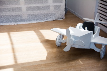 Wooden toy airplane on a wooden floor in the sun in the roomの写真素材