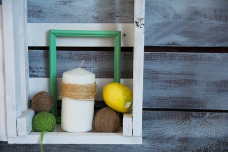 Wooden shelf with tangles of yarn and a candle wrapped in string.の写真素材