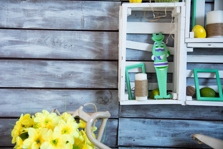 Wooden shelf with tangles of yarn and a candle wrapped in string. Bicycle with yellow flowers on the background of wooden painted boardsの写真素材