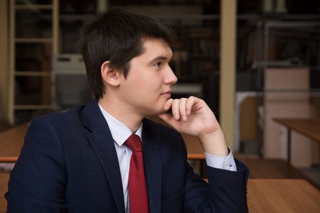 Portrait of a young successful man in a suit. Business man in profile inside the room. Student in the classroomの写真素材