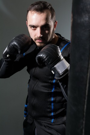Man in boxing gloves in the rack. A boxer in a suit of electric stimulation in the gym.の写真素材