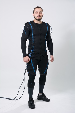 Young fitness man in an electric stimulation suit on a white background in studio in full growthの写真素材