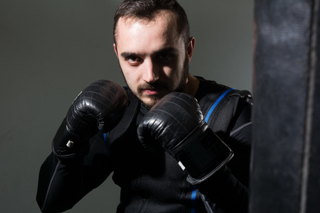 Man in boxing gloves in the rack. A boxer in a suit of electric stimulation in the gym.の写真素材