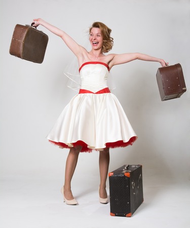 Cheerful bride with suitcases on a light background in the studio. Girl pin up in retro style happyの写真素材