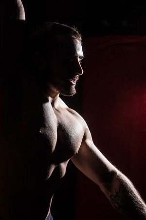 Silhouette of muscular man on dark red background.の写真素材