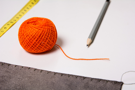 Background for tailor orange thread ribbon and pencil on white tableの写真素材