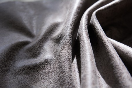 The folds of the fabric with the invoice are illuminated by light. Background of rumpled gray skin