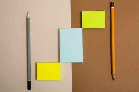 Three multi-colored sticky sticky paper and two pencils on the background