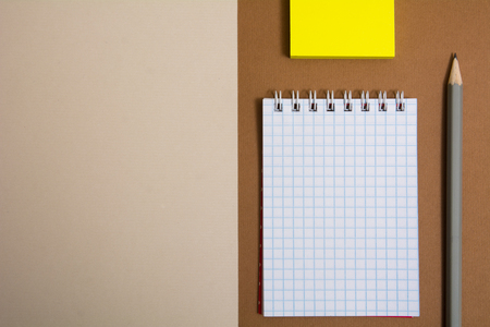 Notepad three different colored sticky papers and pencils on a light backgroundの写真素材