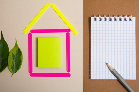 House of counting sticks and a notebook with a pencil. The project of his house with a tree of leavesの写真素材
