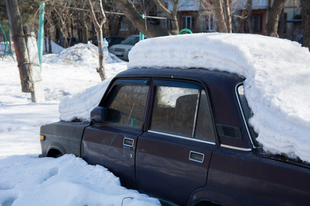 Old abandoned car covered with several layers of snow.の写真素材