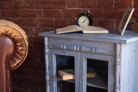 Desk clock with a book on a wooden cupboard against a brick wall background.の写真素材