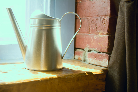 Metal watering can on a wooden window sill.の写真素材