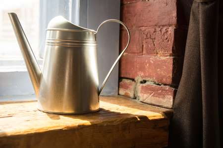 Metal watering can on a wooden window sill.の写真素材