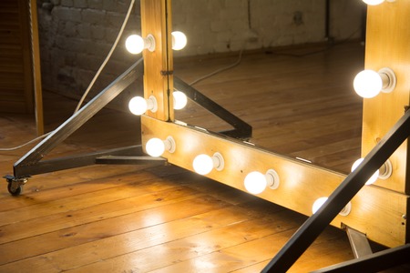 Close-up of a large mirror in a room with a brick wall and a wooden floor.