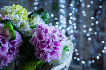 Artificial pink and yellow flowers on bokeh background. Festive still life with a bouquet.の写真素材
