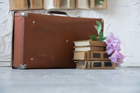 Outdated lilac-colored suitcase on books on the floor.の写真素材