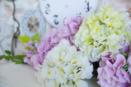 Bouquet of artificial flowers on the background of a wall clock.の写真素材