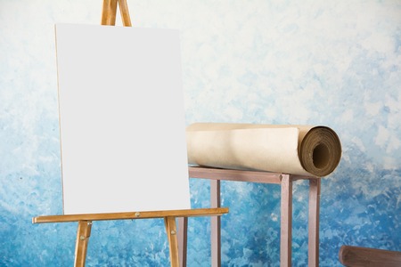 Easel background with a white sheet and a roll of paper for watercolors on a blue background.の写真素材