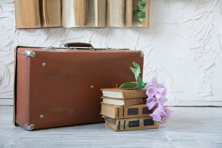 Outdated lilac-colored suitcase on books on the floor.の写真素材