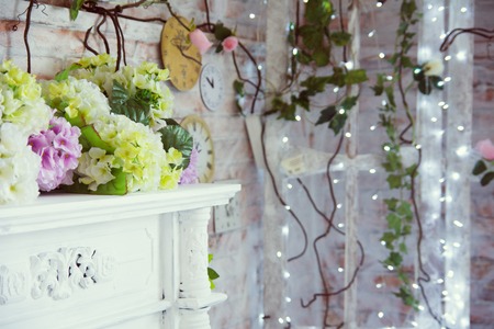 Decorative table with artificial flowers and a background of burning garlands.の写真素材