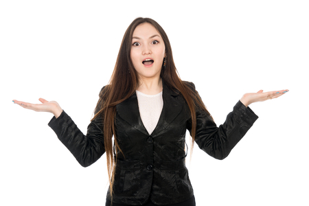 Portrait of a surprised Asian woman with hands to the sides in isolation over white background. Young business woman with open mouth in a dark suitの写真素材