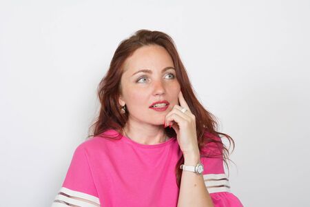 Closeup of a thoughtful red-haired woman looking away isolated on white background.