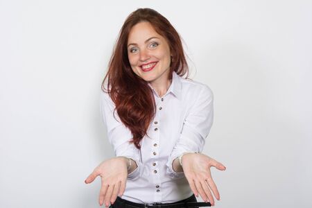 Smiling woman in a light blouse divorced aside hands isolated over a white background.の写真素材
