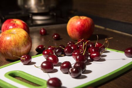 Apples and cherries on a cutting board. Background fruits on the kitchen tableの写真素材