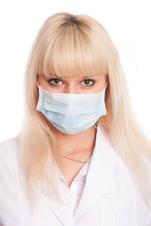 Close up of a young female nurse in mask looking at the camera. Doctor isolated on a white backgroundの写真素材