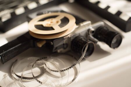 Roll of film with movie camera and movie clapper on light, illuminated table. Filming Accessoriesの写真素材