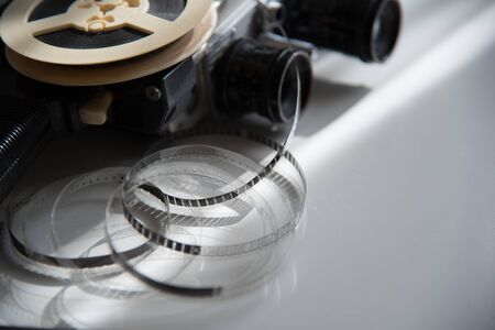 Film roll of film on a reel with a retro movie camera on a light table. Filming Accessoriesの写真素材