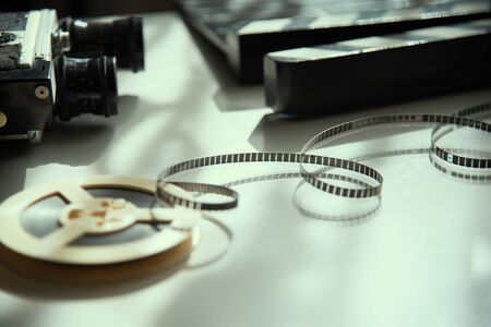 Unwound 8mm film strip on a light background with an old movie camera and clapboard. Movie Accessoriesの写真素材
