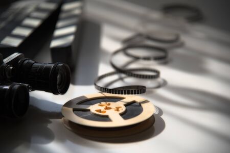 Unwound 8mm film strip on background with old movie camera and movie clapper board. Movie Accessoriesの写真素材