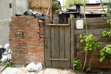 Background old wooden door, brick wall and trash bags. Village slumsの写真素材