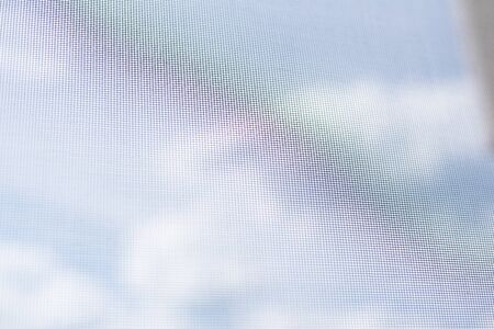 Background view from the window with a mosquito net on the sky with clouds and a rainbow. Virus...