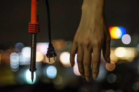 Soldering iron hands and urban night viewの写真素材