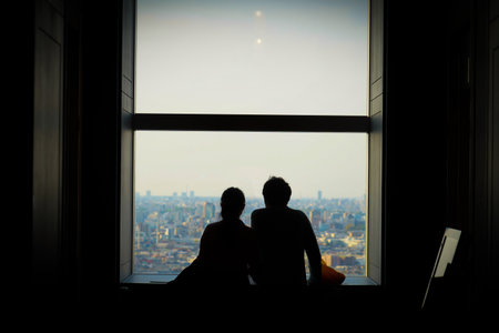 Silhouette of two people looking out at the city. Shooting Location: Setagaya Ward, Tokyoの写真素材