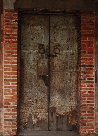 The orange brick wall with old steel doorの写真素材