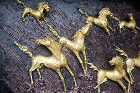 Golden Horses sculptures on the wallの写真素材