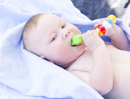 Six month old baby eating toy himself on blue fonの写真素材