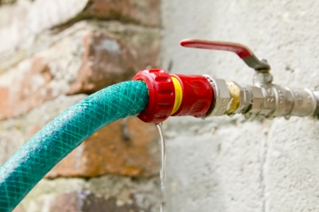 Green garden hose and pump red plastic connectionの写真素材