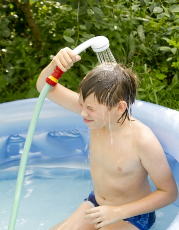 boy in the small blue swimming pool outdoorの写真素材