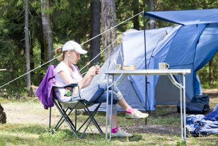 Woman near blue big tent on grass in the forest with living roomの写真素材