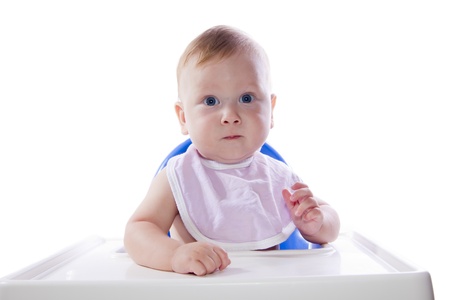 A young blue-eyed child feeding pumpkin puree in a chair for feedingの写真素材